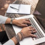personne tapant sur un MacBook Pro sur une table en bois marron pendant la journée photo