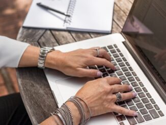 personne tapant sur un MacBook Pro sur une table en bois marron pendant la journée photo