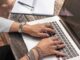 personne tapant sur un MacBook Pro sur une table en bois marron pendant la journée photo
